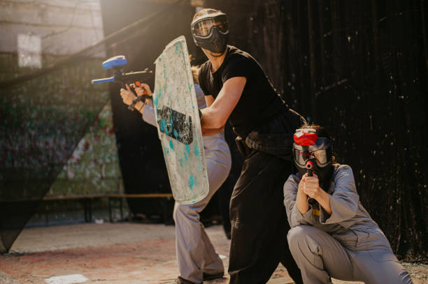 Paintball, shooting and people in action competition, game or match as a competitive team on a battleground. Aim, gun and player or teamwork of group in extreme sports with camouflage and safety mask