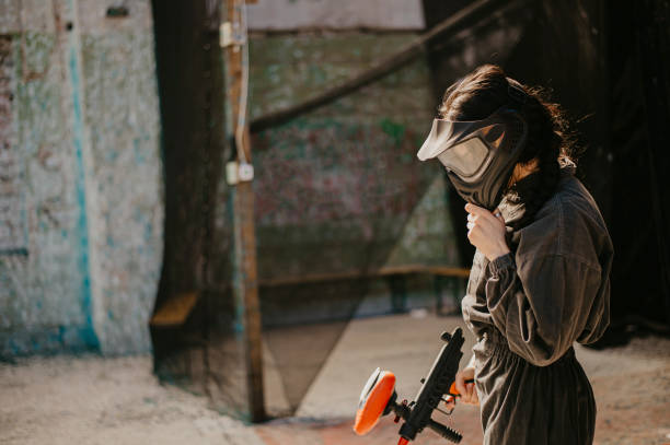 Close-up of a paintball player wearing mask and aiming a weapon. About 25 years old, Caucasian male.