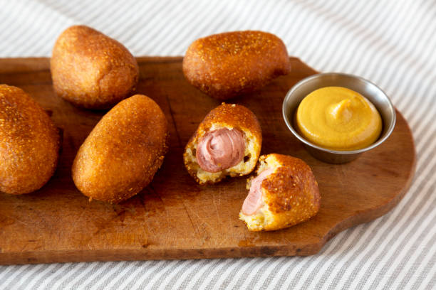 mini perros de maíz caseros en una tabla de madera rústica, vista de ángulo bajo. primer plano. - corn dog fotografías e imágenes de stock