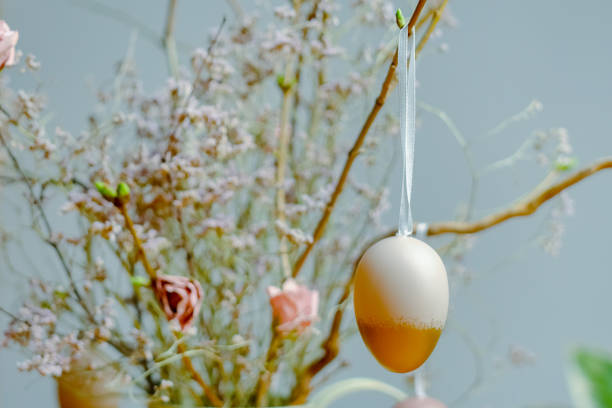 Easter decoration. Hanged coloured Easter egg on plant twig. Selective focus. Easter background.