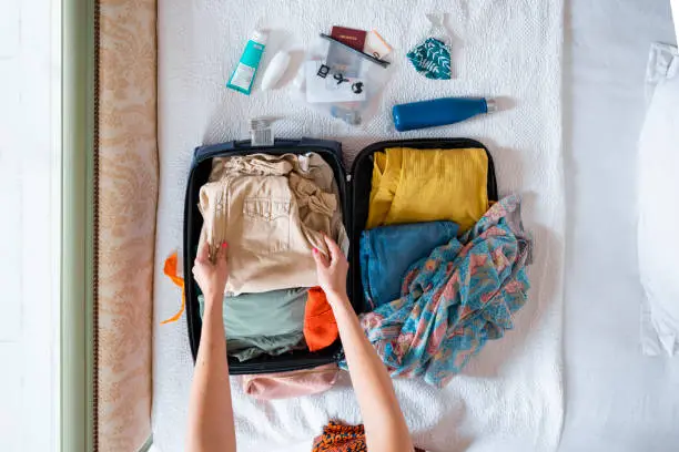 A point of view shot of an unrecognisable caucasian, mid adult woman wearing a dress on a sunny morning. She is unpacking her suitcase in an Air B&B she is staying in on her holidays in the south of France.