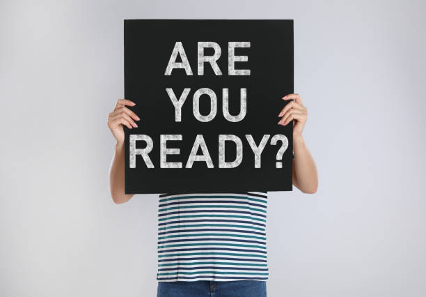 istock Woman holding poster with text Are You Ready? on light grey background 1388967503