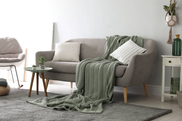 istock Soft knitted blanket on sofa in room. Home interior 1388967759