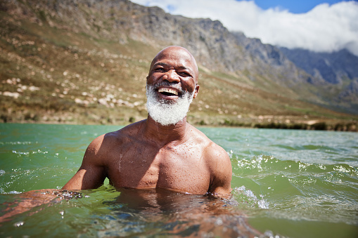 Portrait of a mature African man laughing while swimming in the ocean on a sunny day in summer