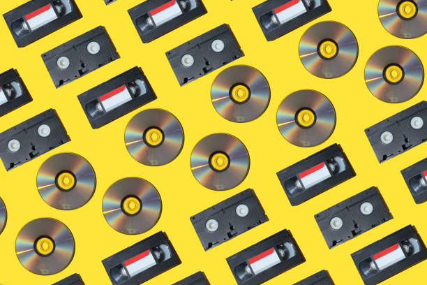 pattern with a vhs video cassette, golden compact disc, outdated technology background. - dvd obsolete cd cd rom imagens e fotografias de stock