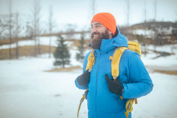 A mountaineer with a backpack on his back and in a ski jacket enjoys a cold winter day. ISL