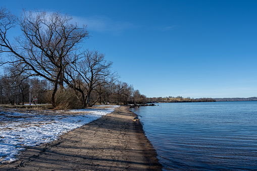 A lake winter beach covered with snow and a blue sky in the background