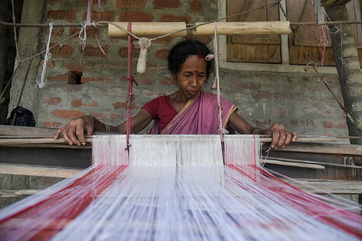 Morigaon, India. 31 March 2022. An Assamese woman weaves Assamese Traditional Gamosa (scarf) in handloom, ahead of Rongali Bihu festival on March 31, 2022 in Mayong, Morigaon,  India. Gamosa is a social identity of the Assamese people which is an essential part during celebration of Bihu festival of Assam.