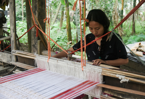 Morigaon, India. 31 March 2022. An Assamese woman weaves Assamese Traditional Gamosa (scarf) in handloom, ahead of Rongali Bihu festival on March 31, 2022 in Mayong, Morigaon,  India. Gamosa is a social identity of the Assamese people which is an essential part during celebration of Bihu festival of Assam.