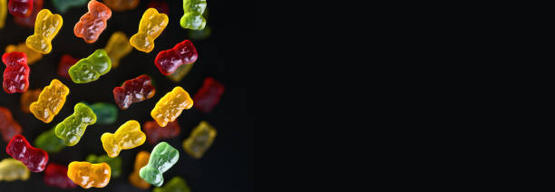 istock Multicolored flying gummy bears on a black background, flat lay. Banner 1388977365
