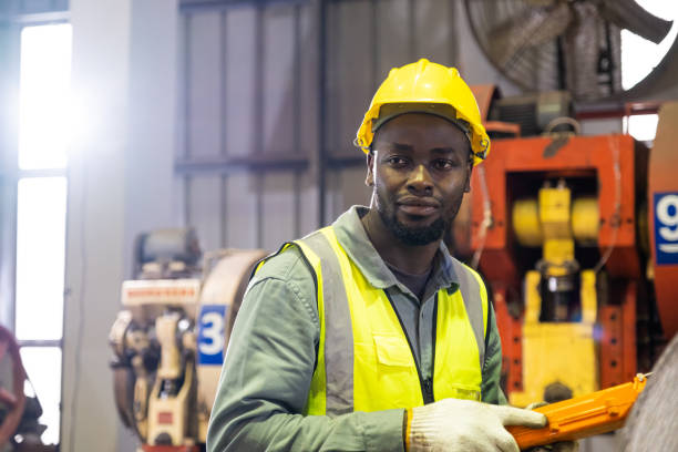 istock African men mechanical engineer, wearing safety equipment. While doing machine maintenance and safety control while work inside of factory area. With blurred background of heavy machine. 1388977934