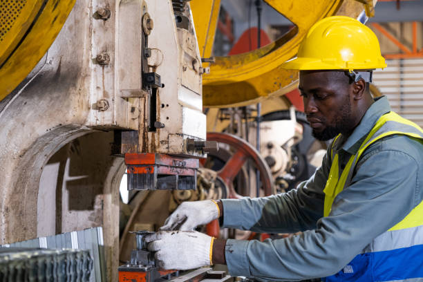 istock African men mechanical engineer, wearing safety equipment. While doing machine maintenance and safety control while work inside of factory area. With blurred background of heavy machine. 1388978114