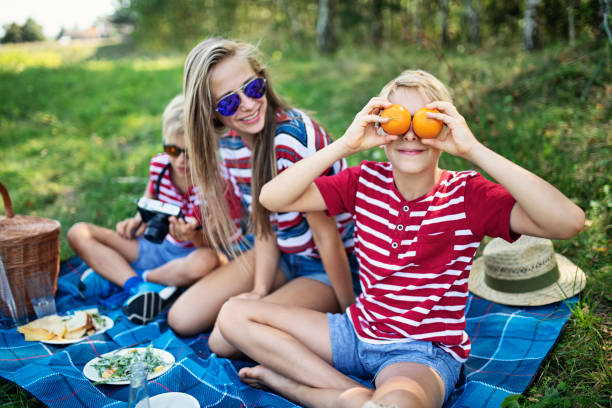 Boy and girl sharing spaghetti in playful picnic scene. Concept of childhood bonding, humorous lifestyle branding, outdoor meal, and joyful emotional connection.