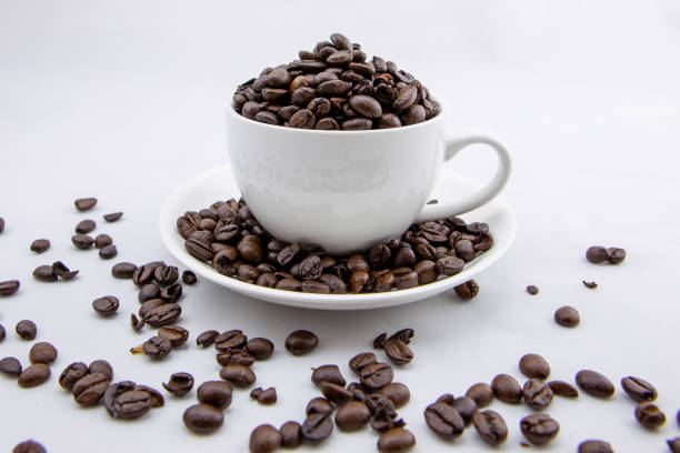 A flavorful coffee scene displaying a cup filled with coffee next to a cluster of coffee beans on a white backdrop