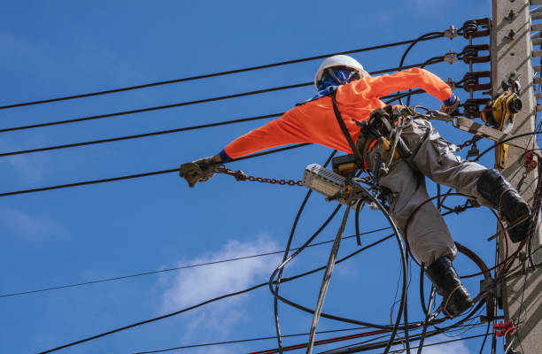 elettricista con attrezzature di sicurezza e strumenti di lavoro sta installando linee di cavi e sistema elettrico sul palo elettrico contro il cielo blu - maintenance engineer fuel and power generation power line electricity foto e immagini stock