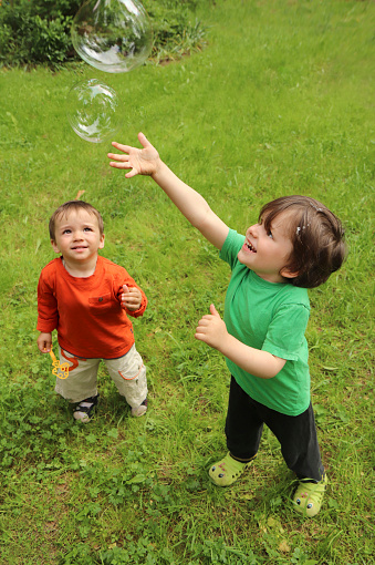 Two small children play with soap bubbles in nature in summer.