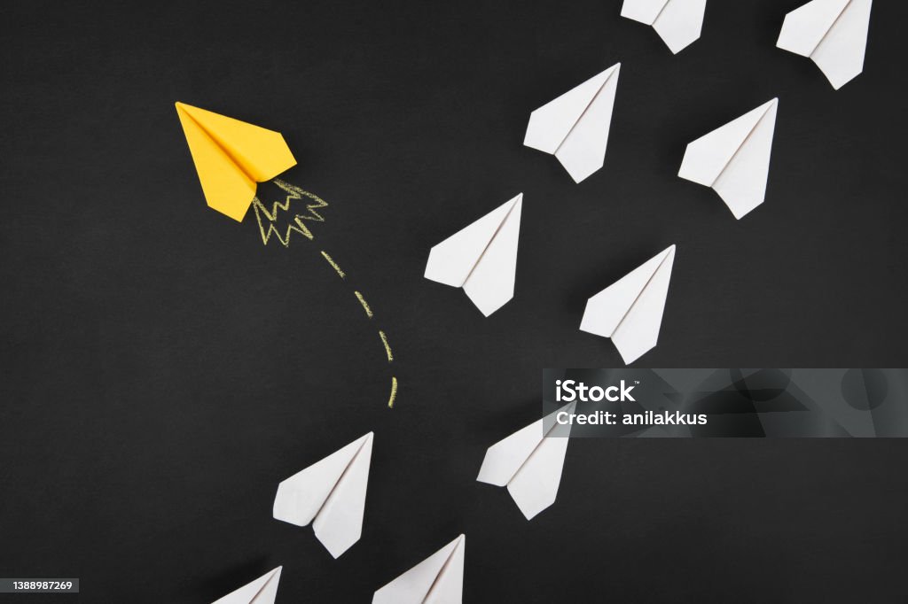 Leadership Concept with Paper Airplanes White colored paper airplanes with one yellow airplane in its own road on chalkboard background Chalk Drawing Stock Photo