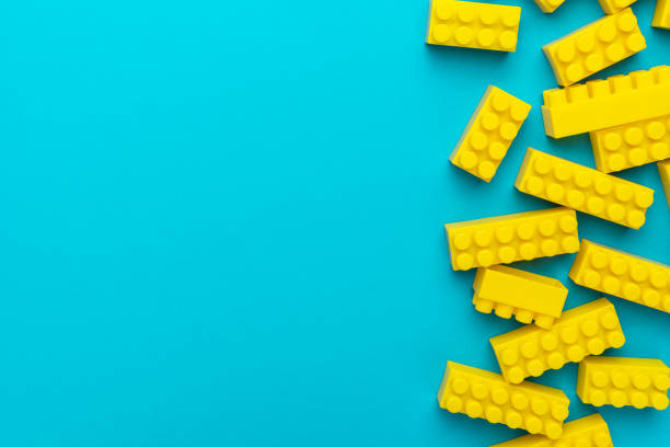 Top view of yellow plastic blocks. Right side composition of yellow building blocks from child constructor. Bright plastic blocks on turquoise blue background with copy space.