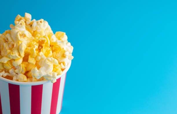 istock Popcorn in a Red and White Striped Container on a Blue Background 1388995188