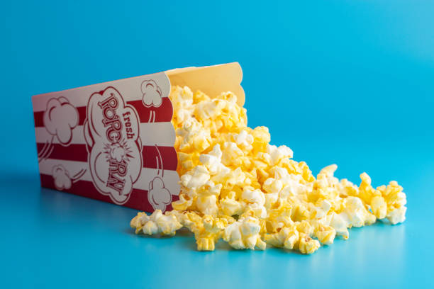 Buttter Popcorn in a Red and White Striped Container on a Blue Background
