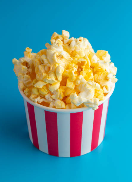 istock Popcorn in a Red and White Striped Container on a Blue Background 1388995283