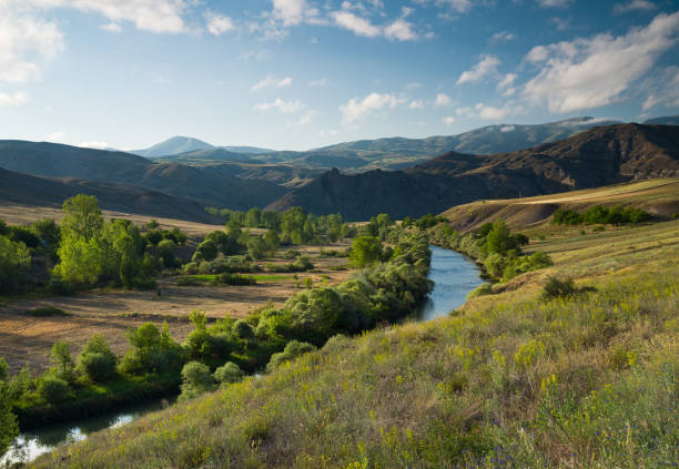 istock Sunrise scene.Summer sunny panoramic landscape with river and green hills 1389003421