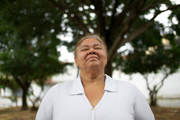 Portrait of a mature woman outdoor, displaying joy and excellence. Behind her there are some trees, as she enjoys the fresh air.p at the park.