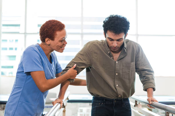 istock Female therapist helps young man learn to walk again 1389017461