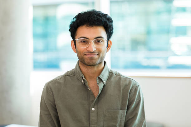 istock Man wearing button down shirt and eyeglasses poses for photo 1389017464