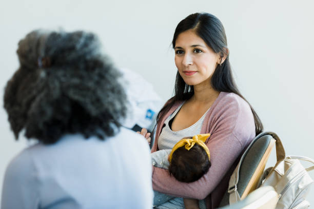 Beautiful woman holds baby and listens to unrecognizable person Mid woman rocks her baby and listens to unrecognizable person talk. postpartum depression stock pictures, royalty-free photos & images