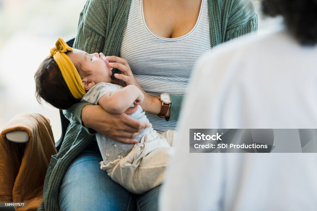 Unrecognizable person rocks baby to sleep Baby looks up at unrecognizable woman putting pacifier in her mouth. Postpartum Depression Stock Photo