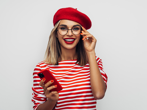 Sensual french woman wearing red beret and holding a smart phone