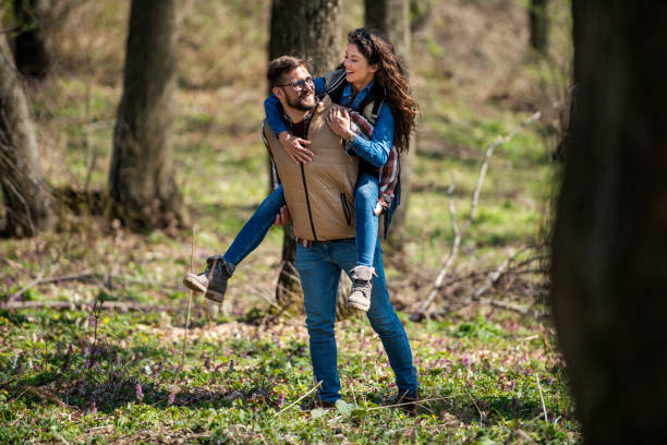 Carefree couple having fun while holding hands and running in spring day outdoors.