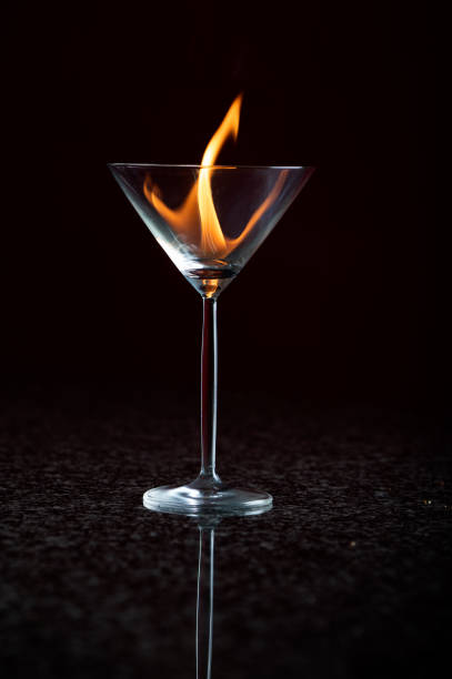 ein einzelnes martiniglas auf einer reflektierenden oberfläche mit schwarzem hintergrund - martini brand vermouth stock-fotos und bilder