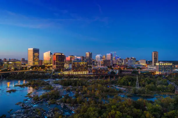 Downtown Richmond skyline aerial at dusk with the Falls Of The James rapids and urban forests in the foreground.