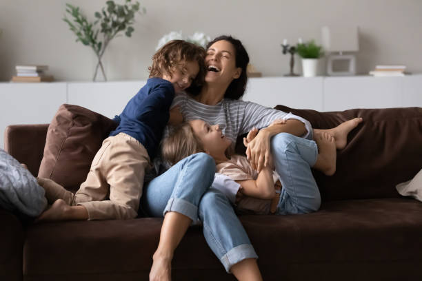istock Overjoyed mother with two kids having fun on comfortable couch 1389029734