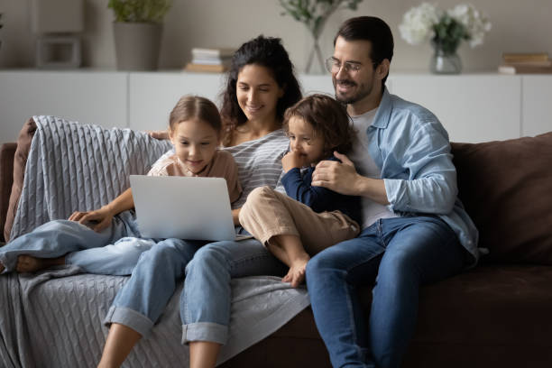 istock Happy parents with kids using laptop at home together 1389029742