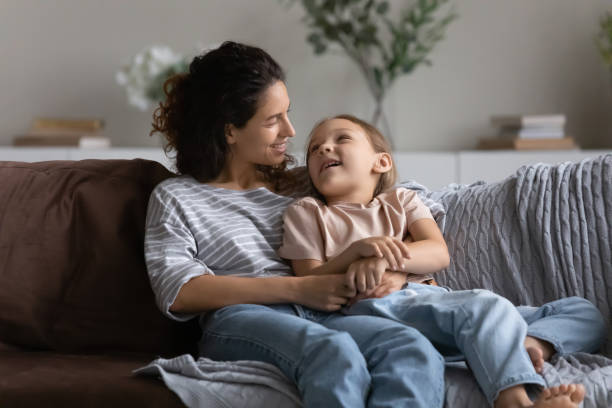 istock Happy mother with daughter hugging, relaxing on comfortable couch 1389029748