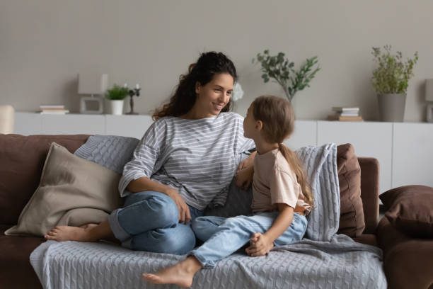 istock Smiling mother with little daughter talking, sitting on comfortable couch 1389029752