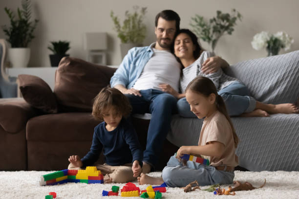 istock Two little kids together while parent relaxing on comfortable couch 1389029761