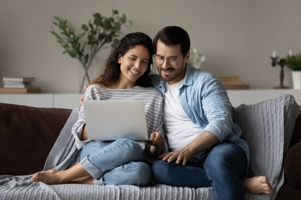 istock Happy young couple using laptop, relaxing on couch together 1389029774
