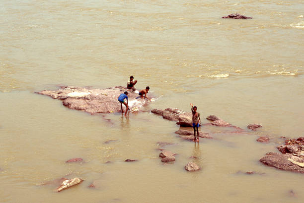 Uttar Pradesh, India - aug 11, 1996:  Indian children play in the waters of a river and greet passing travelers.  Vintage photo. Historical archive photo.