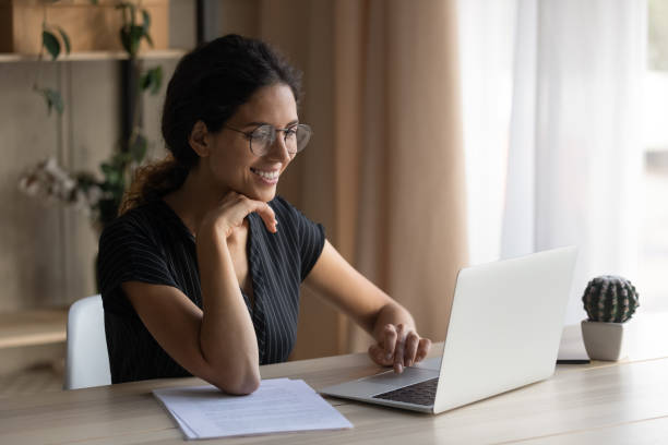 istock Smiling Hispanic woman work online on computer at home 1389032736
