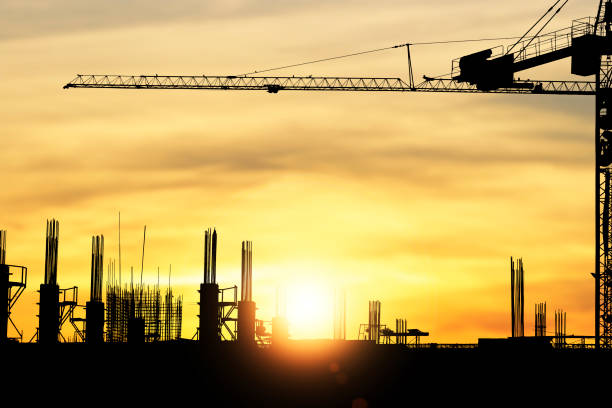 istock Silhouette construction site with a crane on yellow background and the sunset glows through in the evening 1389035485
