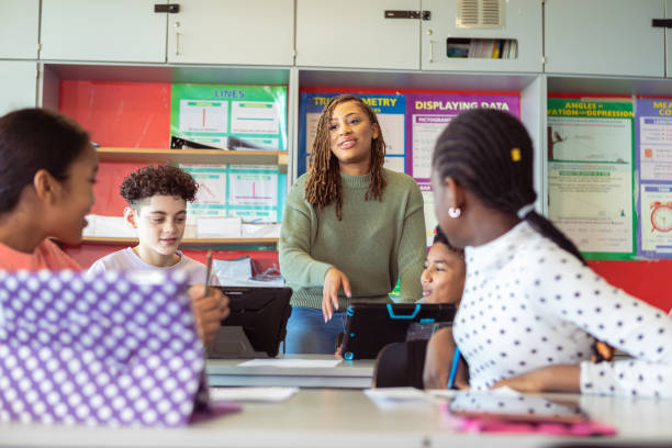 insegnante che risponde alle domande mentre gli studenti lavorano in classe - educazione secondaria di scuola media foto e immagini stock