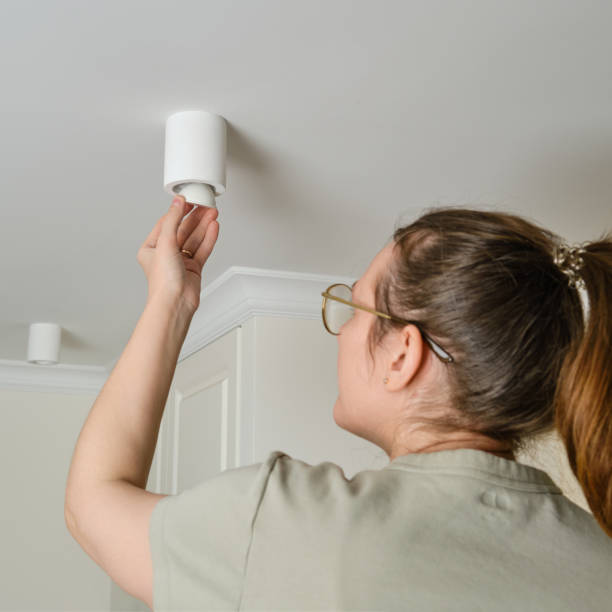 istock A woman changes a ceiling energy saving light bulb with LED light lamp in a home living room. Work at height self, diy 1389038258