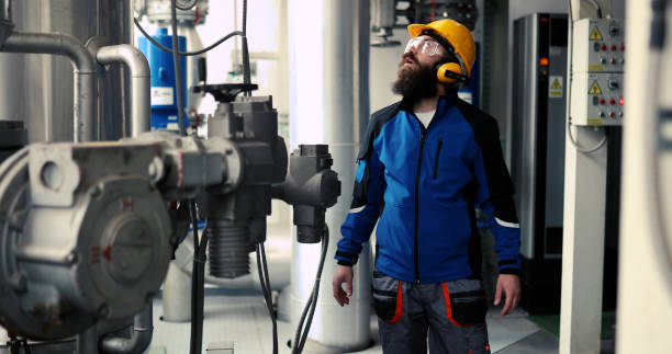 istock Technician worker of heating system in boiler room wearing antiphons. 1389038331