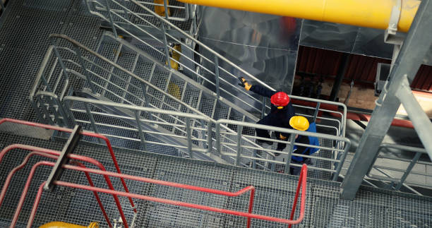 istock Two unrecognizable power plant workers climb upstairs. 1389038339