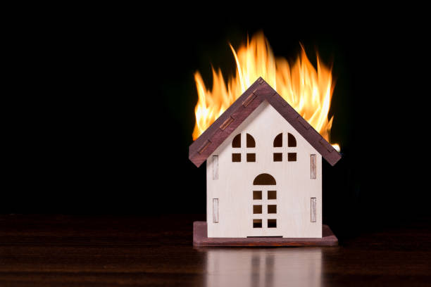 istock Model house in fire on black background with copy space. 1389051869