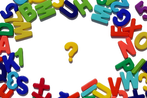 Bright multi-colored letters lie on a white background. There is a question mark in the middle.